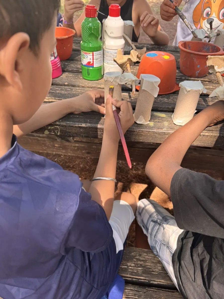 Bambini al lavoro attorno a un tavolo durante un laboratorio manuale all'aperto