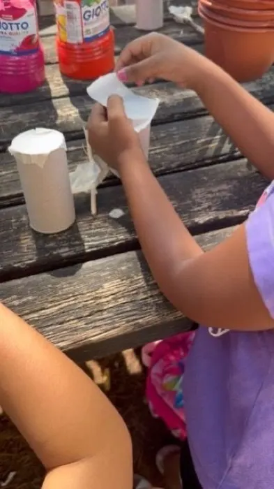 Mani di bambini al lavoro con carta e colori attorno a un tavolo